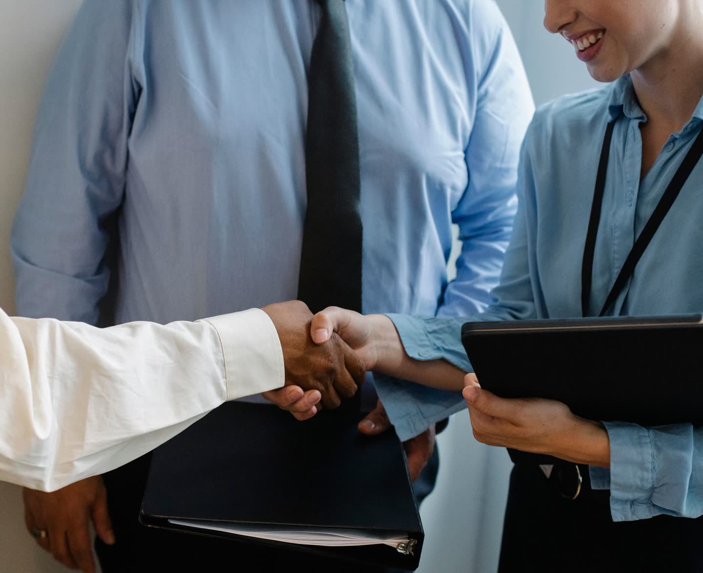 Two partners shaking hands on an agreement while their team looks on